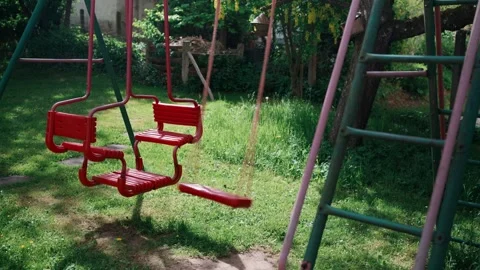 Empty Red Swing Gently Swaying in Garden Vídeo Stock 335142280