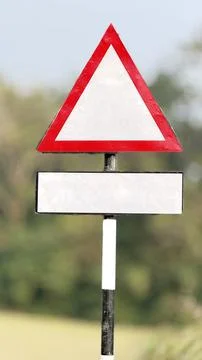 An empty red triangular warning sign and a white rectangular panel stand on a Foto stock