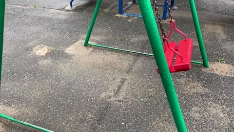 Empty red wooden swing swinging in the rain Stock Footage 166314151