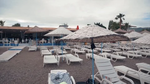 Empty resort, sun beds and umbrellas on cloudy weather.  Stock Footage 109125115