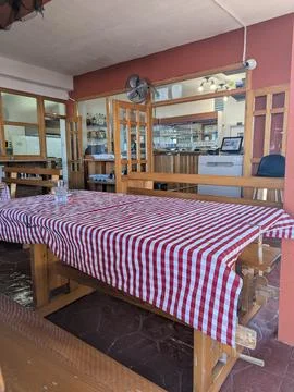 Empty restaurant dining room with red checkered tablecloths and wooden benche Stock Photos
