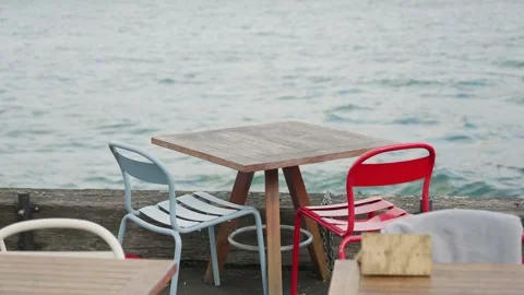 Empty restaurant or cafe table and chairs next to lake or river waters in winter Stock Footage 289416411