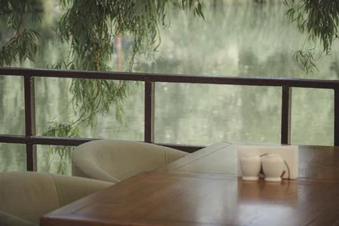 Empty restaurant table with willow branches over a blurred river background Stock Photos