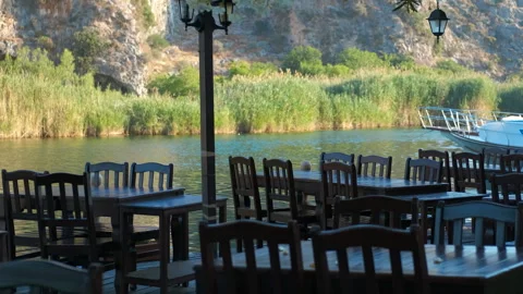 Empty restaurant tables by the river await customers Stock Footage 315055685