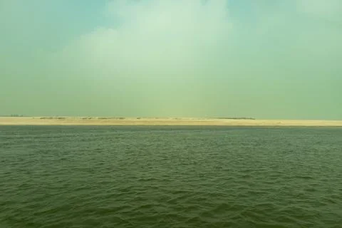 Empty river water landscape with vast sandy bank against blue sky. Stock Photos