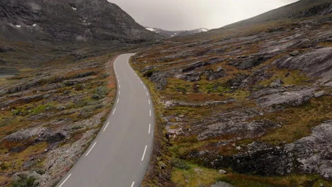 Empty road between mountains with rock and yellow grass 動画素材 255731384