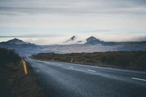 Empty road in front of a mountain range with fog. Lovely landscape and toug.. Stock Photos