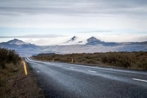 Empty road in front of a mountain range with fog. Lovely landscape and toug.. Stock Photos