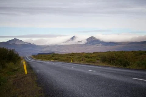 Empty road in front of a mountain range with fog. Lovely landscape and toug.. Stock Photos