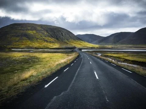 Empty road in front of a mountain range with fog. Lovely landscape and toug.. Stock Photos