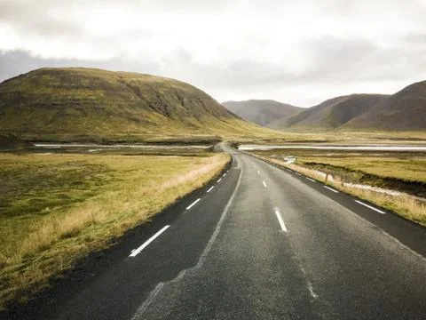 Empty road in front of a mountain range with fog. Lovely landscape and toug.. Stock Photos