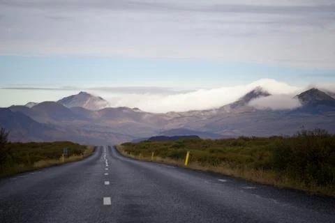 Empty road in front of a mountain range with fog. Lovely landscape and toug.. Stock Photos