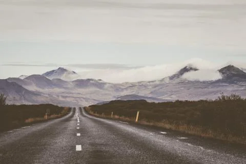 Empty road in front of a mountain range with fog. Lovely landscape and toug.. Stock Photos
