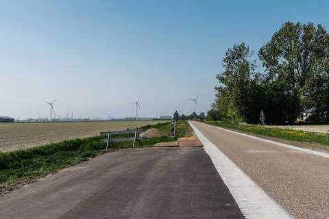 Empty road in Holland between fields and windmills Stock Photos