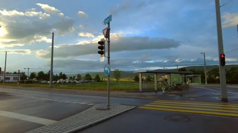 Empty road intersection with traffic lights and a bus stop under a cloudy sky Stock Footage 334865405