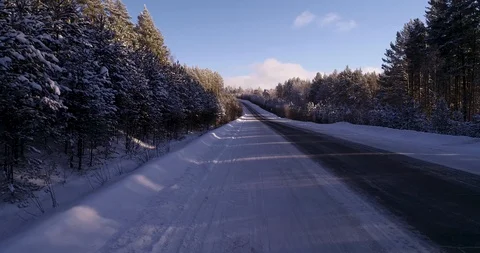 Empty road in the middle of a frozen and snow-covered forest Stock Footage 104482968