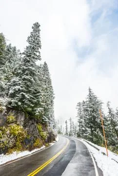 Empty road to the mountain with snow covered landscape in winter season. Stock Photos