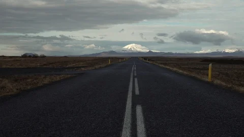 Empty road pointing toward snow covered Hekla volcano Iceland day Stock Footage 110822338