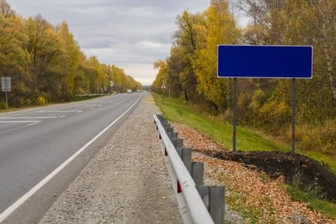 Empty road sign on the side of the road, trails with passing cars Stock Photos