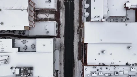 Empty road in snowy winter town with snow-covered roofs of houses and homes Video stock 328998712