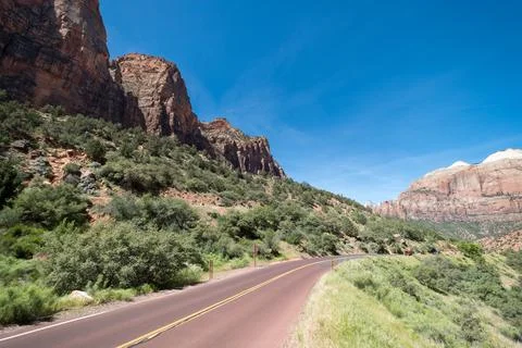 Empty road with some big mountains on one side of the road, close to Zion Nat Stock Photos