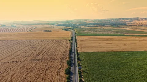 Empty road stretches through fields under a clear sky at sunset Stock Footage 340958704