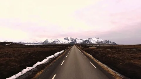 Empty road through barren landscape toward snowy mountains Stock Footage 340962662
