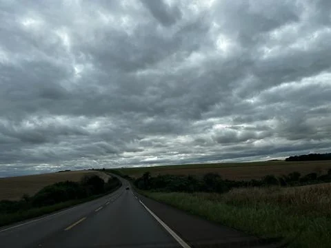 Empty road through rural fields under dramatic cloudy sky in Rio Grande do .. Stock Photos