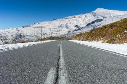 Empty road towards the snow-covered Sierra Nevada mountains. Granada, Spain Stock Photos