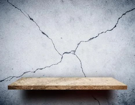 Empty Rock display shelf on cracked cement wall 库存照片