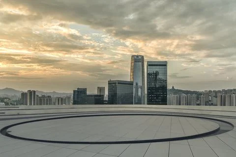 Empty roof deck with a circle pattern against a city skyline at sunset Stock Photos