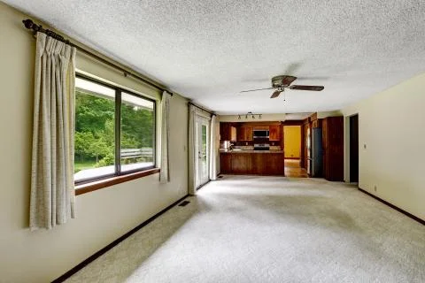 Empty room with carpet floor connected to kitchen with dark brown wooden cabi Stock Photos