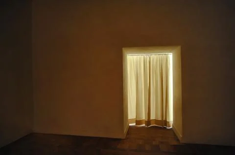 Empty room in dim light and doorway with white curtain to lighter exterior Stock Photos