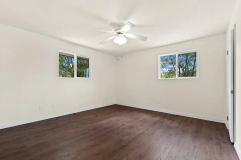 An empty room featuring a ceiling fan and two windows that illuminate the spa Stock Photos
