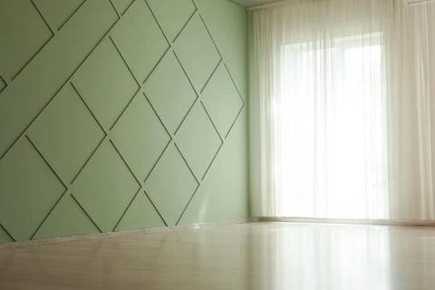 Empty room with green diamond patterned wall and sheer curtains Stock Photos