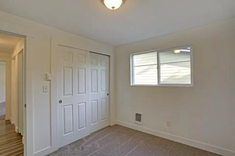 Empty room interior with built in closet, wall to wall carpet and a small win Foto stock