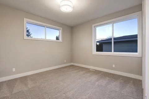 Empty room interior with grey walls paint color and grey wall to wall carpet flo Stock Photos