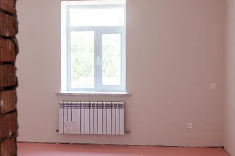 Empty room interior with light-colored walls, a large window, and a radiato.. Stock Photos