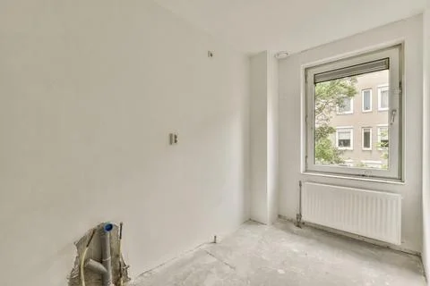 An empty room with a large window and a radiator Stock Photos