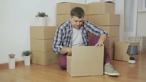 In an empty room, a man opens a cardboard box Stock Footage 86658190
