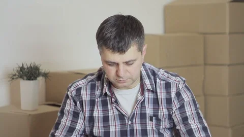 In an empty room, a man opens a cardboard box Stock Footage 86767418