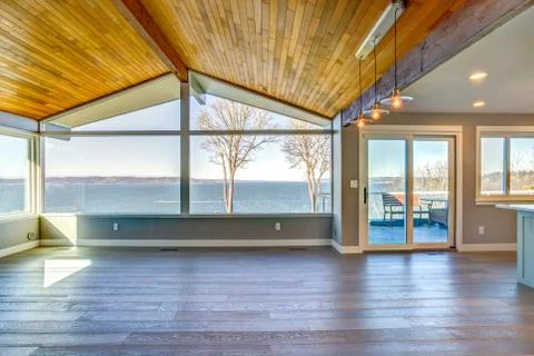 Empty room with planked vaulted ceiling and scenic water view. Stock Photos