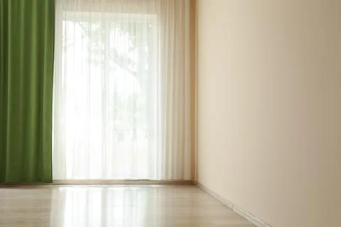 Empty room with sheer and green curtains on window Stock Photos
