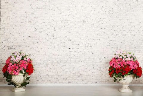 Empty room with white brick wall and beautiful flowers in pots Stock Photos