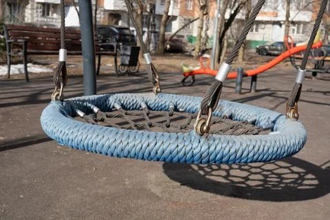 Empty rope swing bathed in sunlight on a public playground Stock Photos