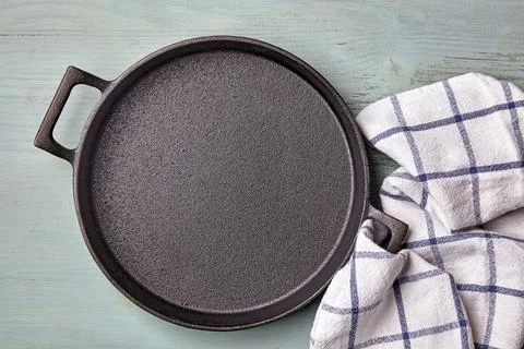 Empty round cast iron pan, tea towel on a light blue wooden table Stock Photos
