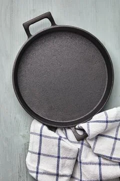 Empty round cast iron pan, tea towel on a light blue wooden table Stock Photos