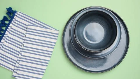 Empty round ceramic plate and kitchen towel on green background, top view 스톡 사진