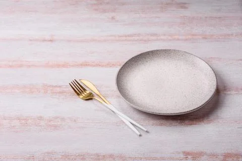 An empty round ceramic plate on a dark, textured white background. An empty.. Stock Photos