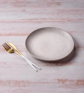 An empty round ceramic plate on a dark, textured white background. An empty.. Stock Photos